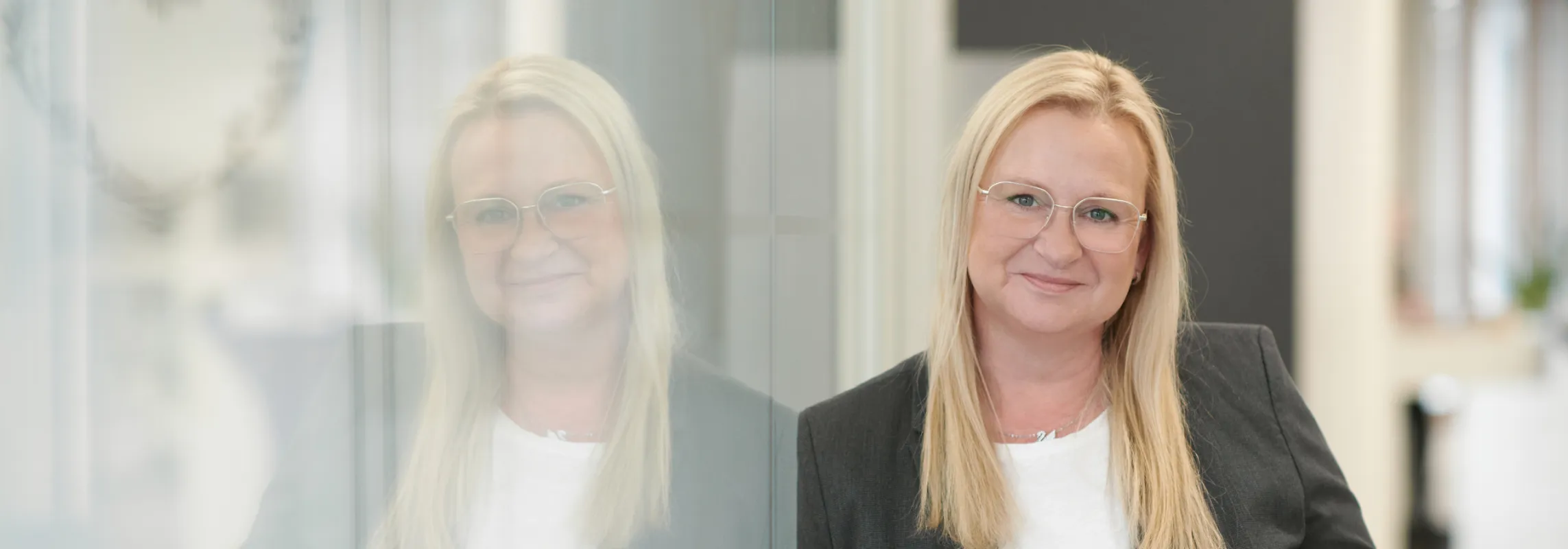 Portrait einer Beraterin der Vereinten Volksbank vor einer Glaswand in der Filiale